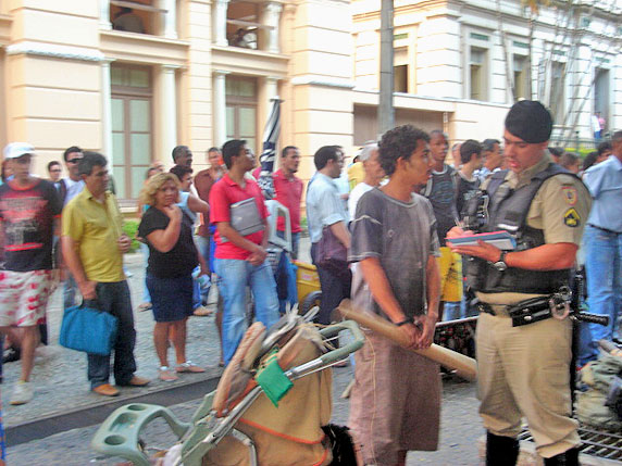 Foto do policial pegando depoimento de um hippie e v?rios curiosos atr?s