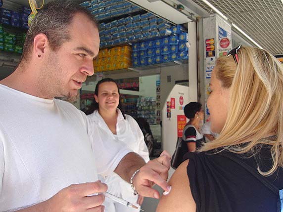 Foto de mulher loira sendo vacinada por enfermeiro