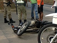 Moto ca?da no ch?o, policiais e algumas pessoas em volta